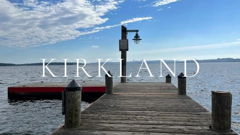 Wooden public dock with vintage marine lamp on Lake Washington in Kirkland, WA, looking out toward the distant Seattle skyline.