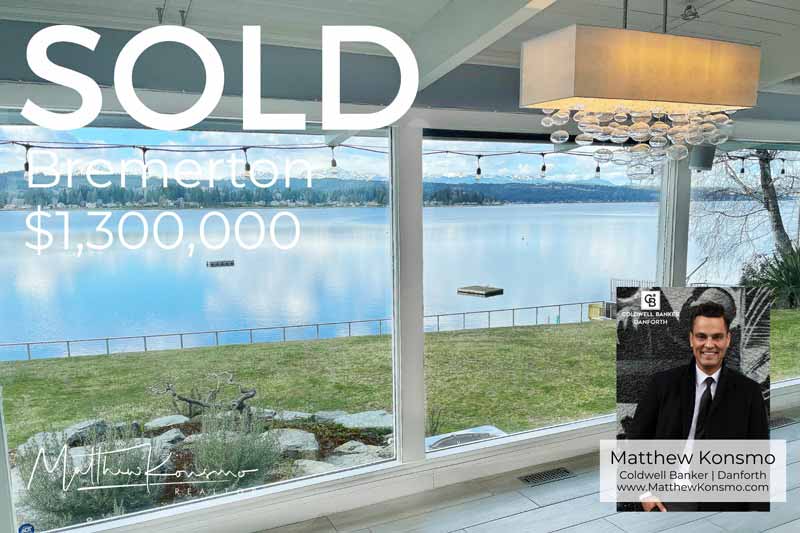 Sold marketing graphic for a Bremerton waterfront home at $1,300,000, showcasing an interior wall of windows framing Puget Sound and Olympic mountain views — professionally represented and sold by Matthew Konsmo, broker with Coldwell Banker Danforth.