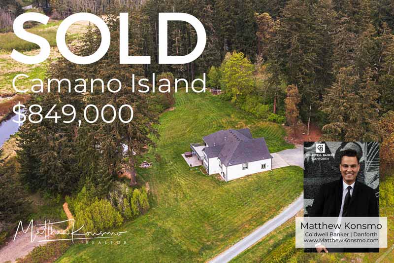 Sold marketing graphic for a Camano Island residential acreage property at $849,000 — aerial view of single-family home surrounded by mature evergreens, professionally represented and sold by Matthew Konsmo, broker with Coldwell Banker Danforth.