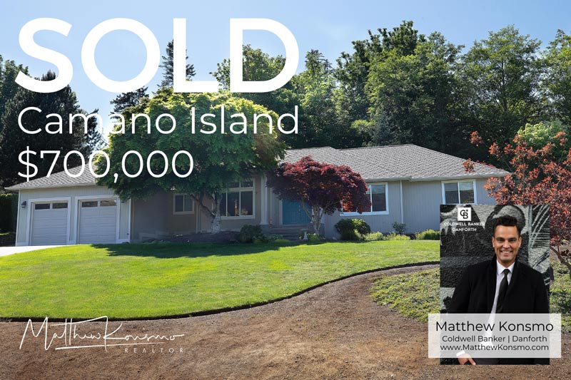 Sold marketing graphic for a single-family rancher on Camano Island, WA — two-car garage, manicured lawn, and Japanese maples — closed at $700,000 by Matthew Konsmo, Coldwell Banker Danforth.