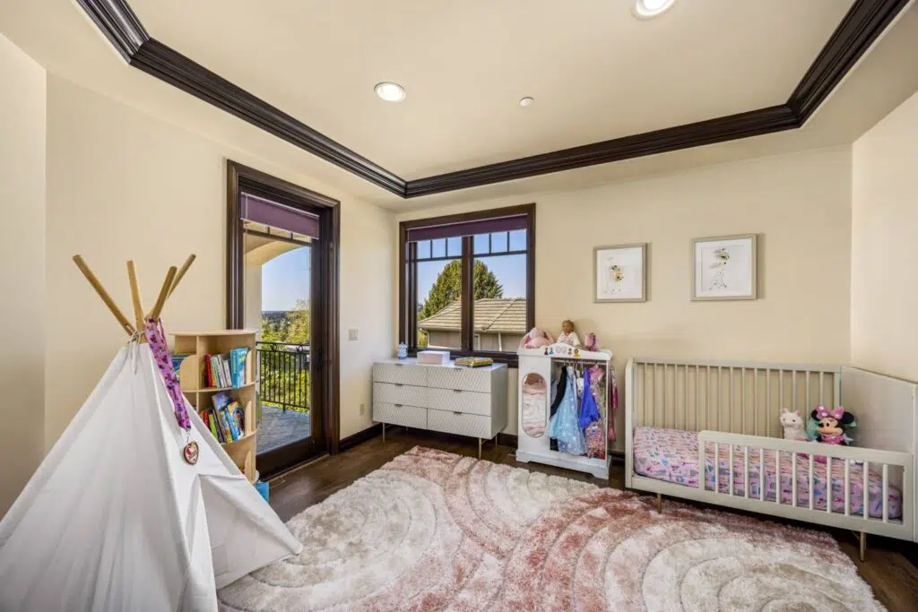 Bright upper-level bedroom with private balcony access, elegant ceiling detail, and large windows offering abundant natural light.