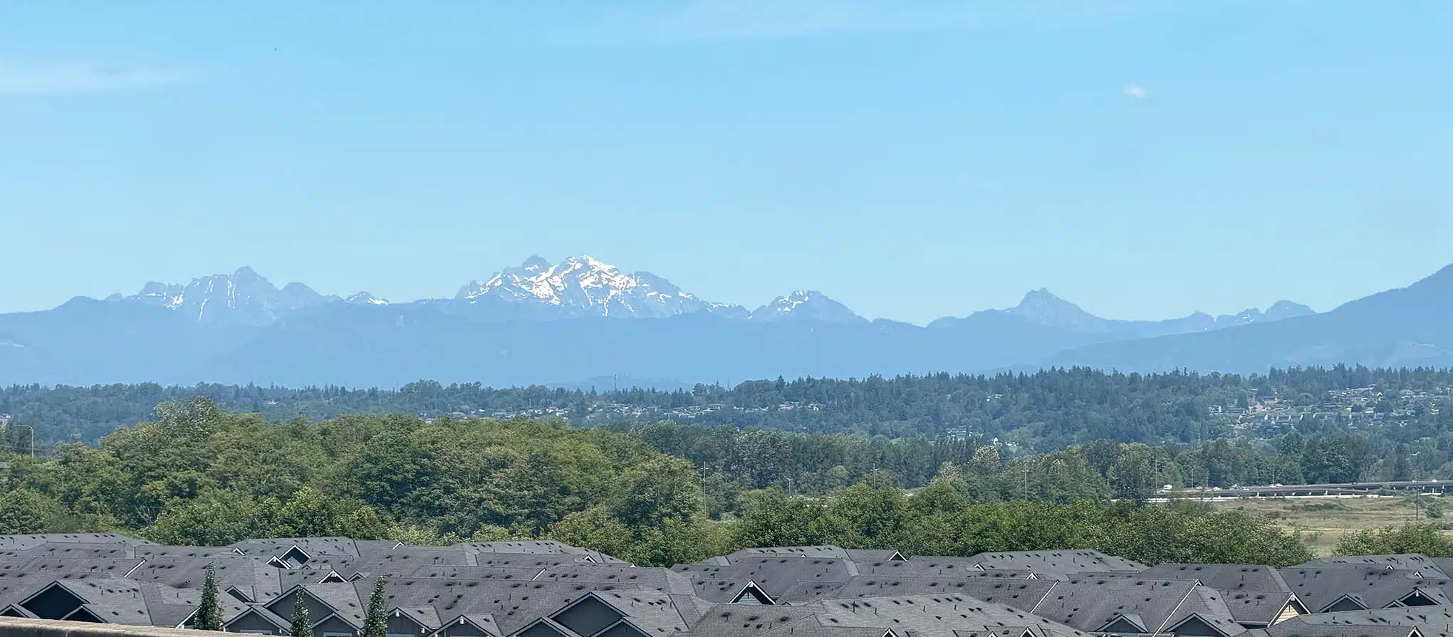Living in Everett, WA: Your 2026 Neighborhood & Real Estate Guide 1 Snow-capped Cascade mountain peaks rising beyond forested foothills and residential rooftops, viewed looking east from Everett, Washington