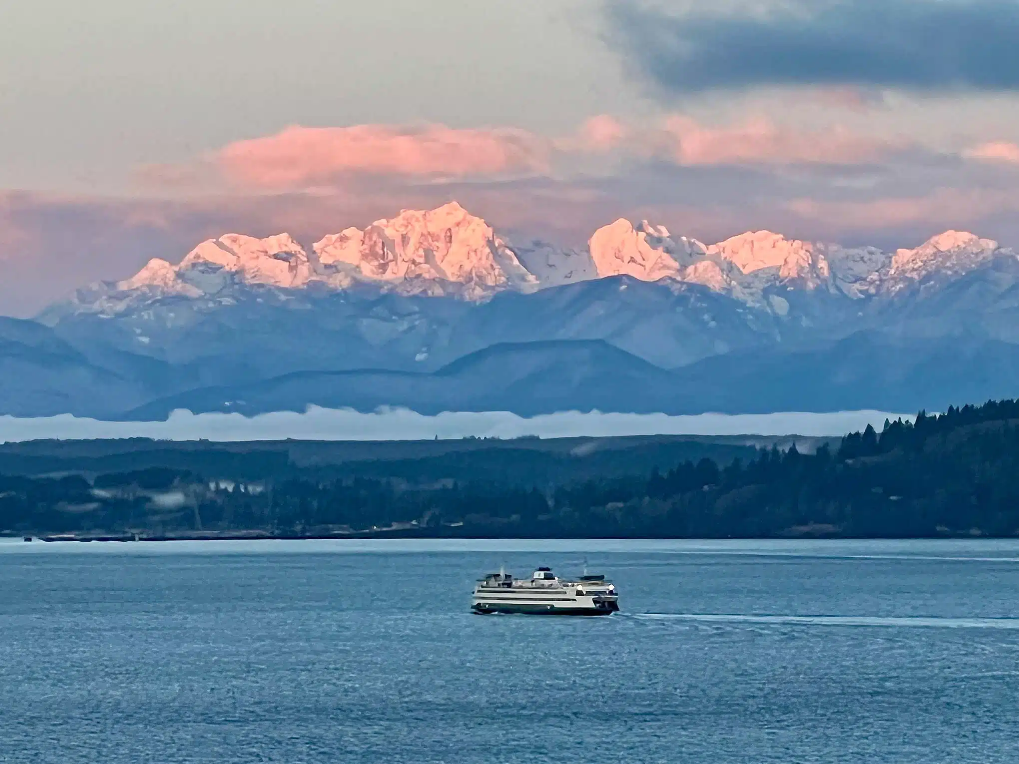 Living in Edmonds, WA - Your 2026 Neighborhood & Real Estate Guide 2 A Washington State Ferry crosses Puget Sound below the Olympic Mountains glowing pink at sunset, viewed from Edmonds, Washington.